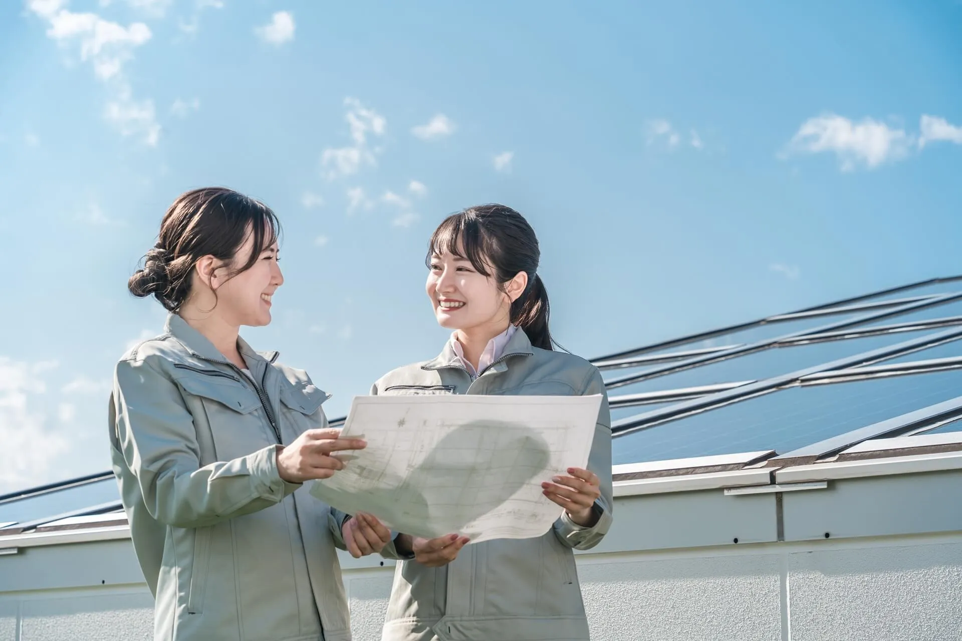 設計図をみている作業着を着た2人の女性