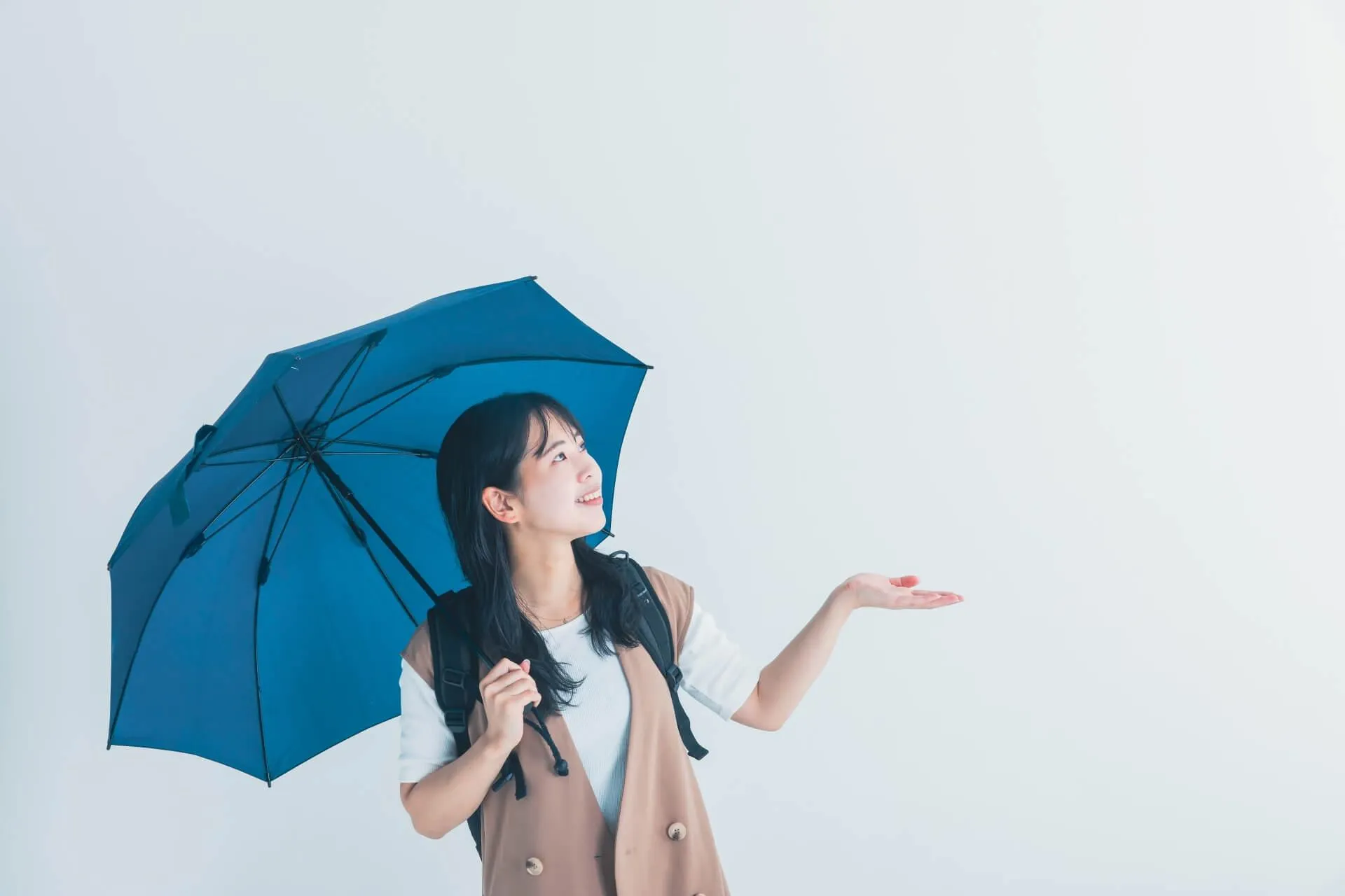 天気を確認する青い傘をさした女性