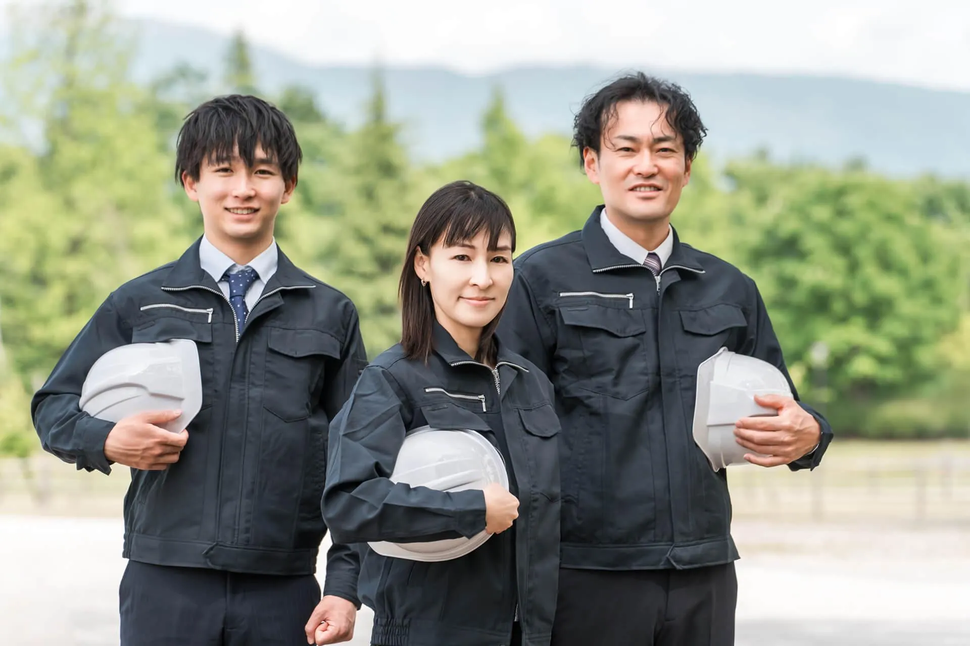 黒い作業着と白いヘルメットを持つ3人の会社員