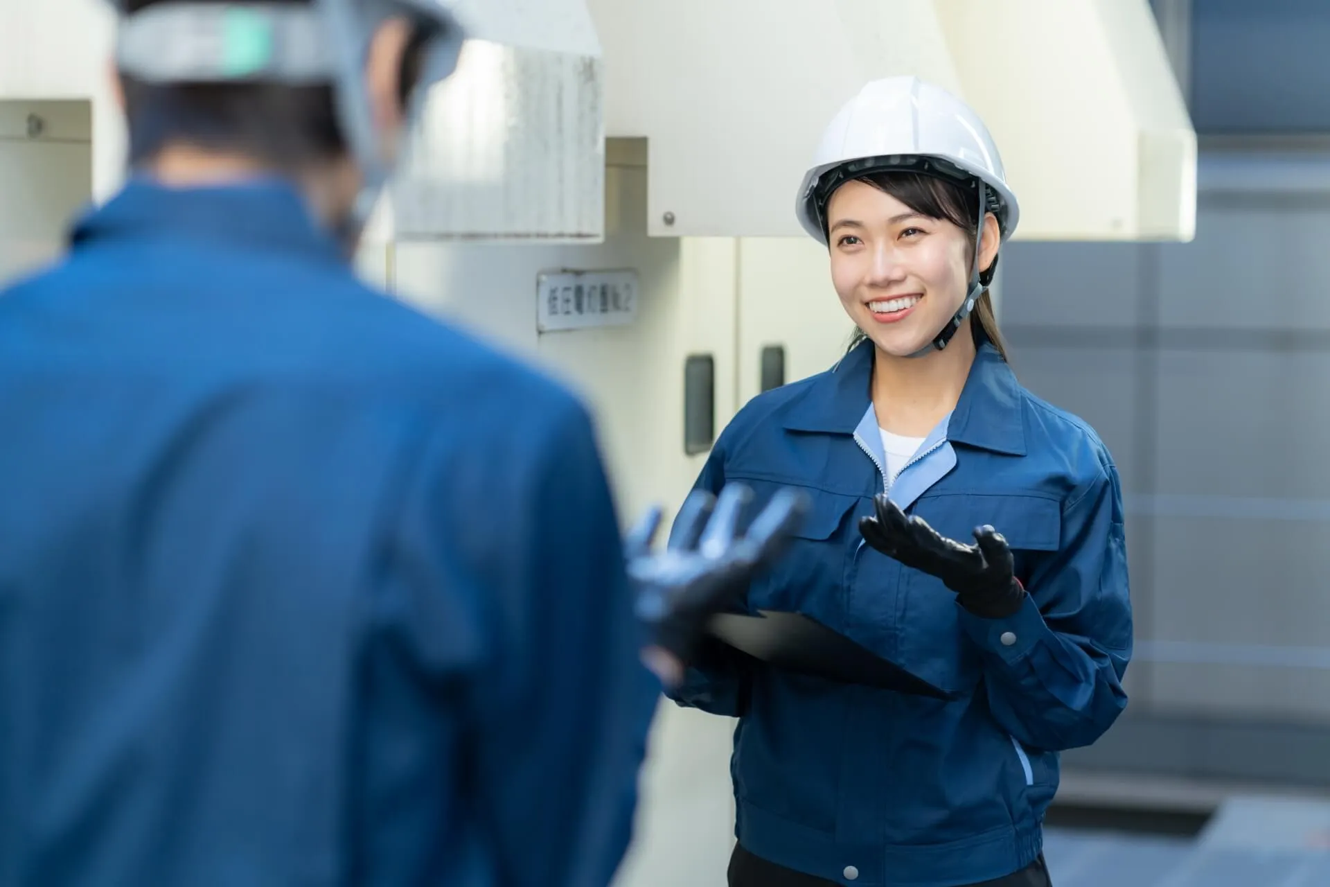 ヘルメットを被った青い作業着を着た女性