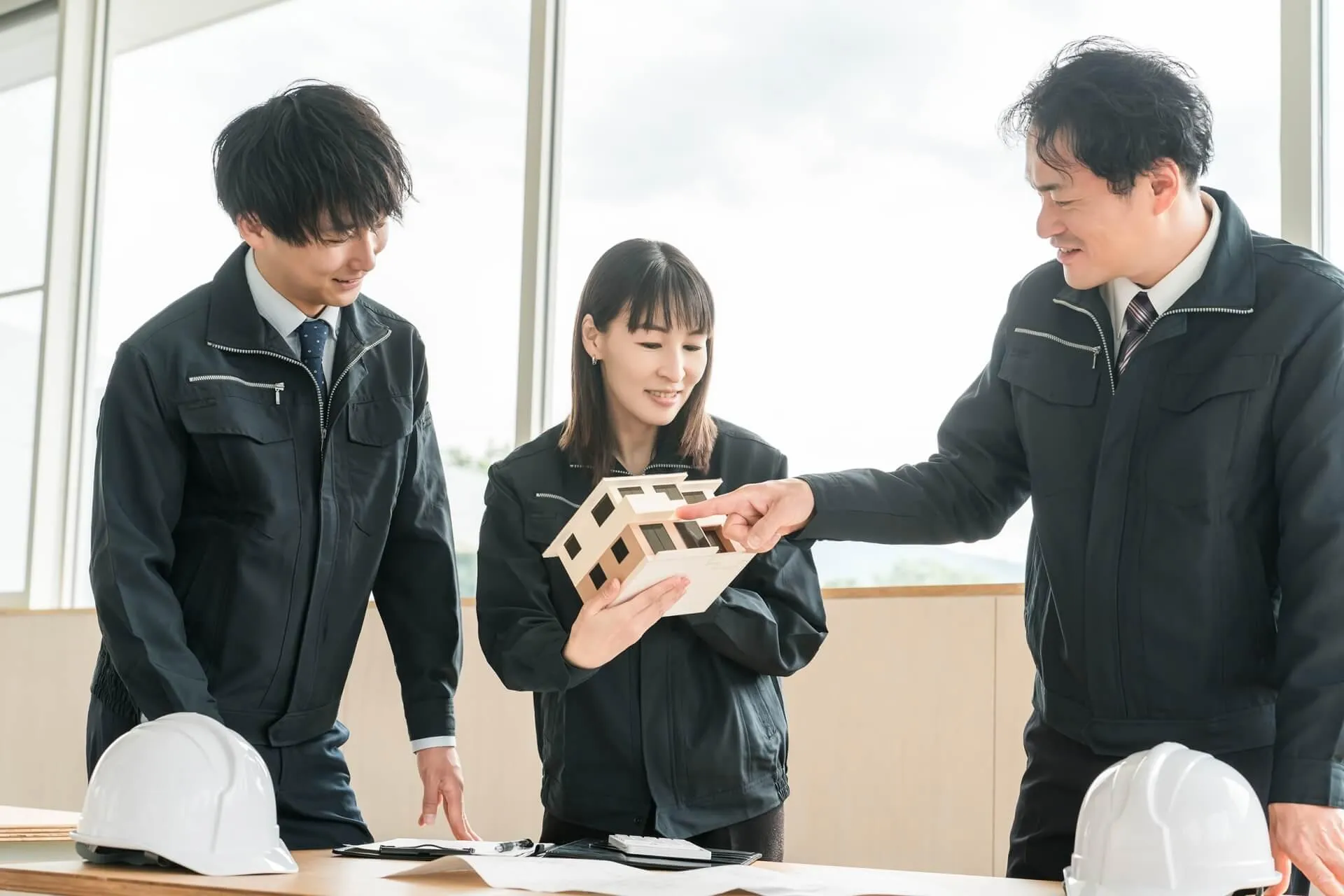 家の模型を使用して打ち合わせをする建設会社のスタッフら